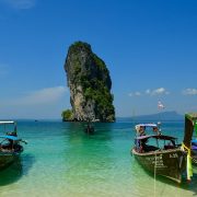 Longtail boats on turquoise water near a limestone island