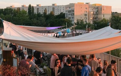 Crowd dancing on a wooden deck under a canopy