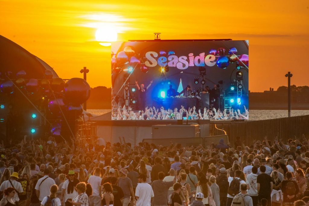 Outdoor music festival crowd at sunset